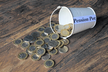 a pound coin in a pile of cash saved in a pension pot.