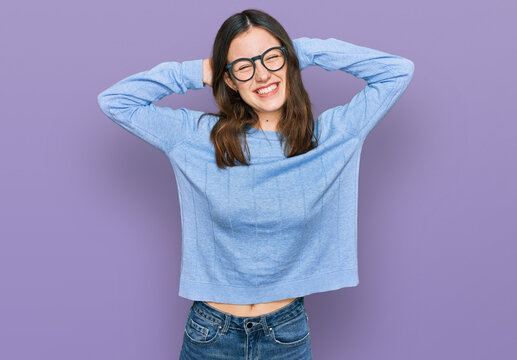 Young beautiful woman wearing casual clothes and glasses relaxing and stretching, arms and hands behind head and neck smiling happy