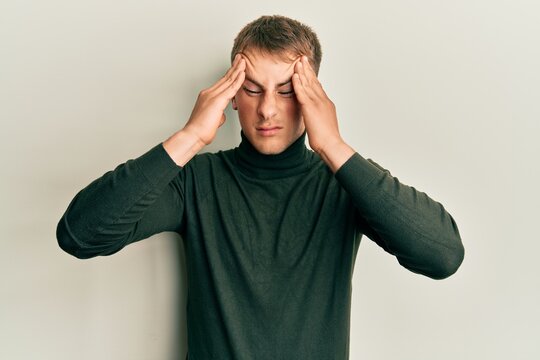 Young caucasian man wearing casual clothes with hand on head, headache because stress. suffering migraine.