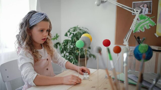 Little concentrated girl making a solar system model at home, homeschooling.