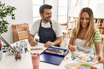 Fototapeta premium Two students smiling happy painting sitting on the table at art school.