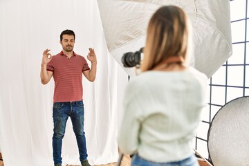 Fototapeta premium Woman photographer talking pictures of man posing as model at photography studio relax and smiling with eyes closed doing meditation gesture with fingers. yoga concept.