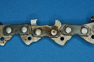 part of old dirty gray iron electric saw in brown rust on blue background