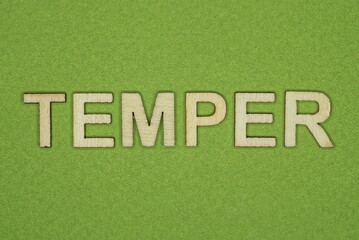gray word temper from small wooden letters on a green table