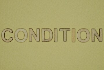 word condition made from wooden letters lies on a yellow table