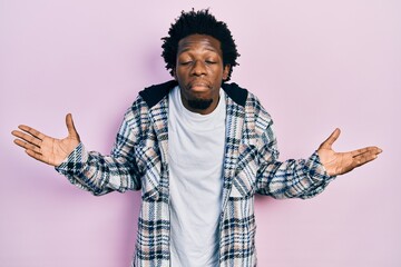 Young african american man wearing casual clothes clueless and confused with open arms, no idea and...