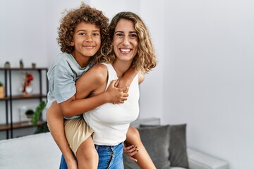 Mother and son smiling confident holding kid on back at home