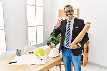Middle age hispanic business man holding paper blueprints smiling cheerful showing and pointing with fingers teeth and mouth. dental health concept.