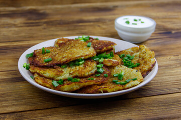Potato pancakes with sour cream on a wooden table
