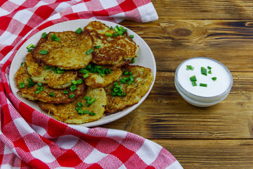 Potato pancakes with sour cream on a wooden table