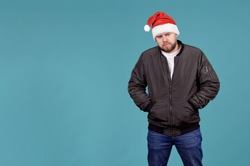 a young man in a Santa hat and a black jacket stands angrily looking at the camera