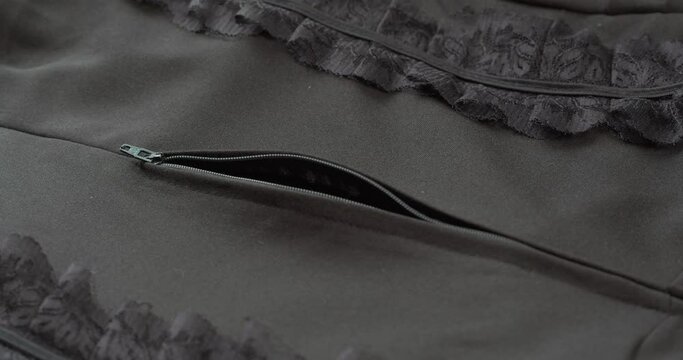 Hand zipping up black blouse with lace guipure close-up. Tailoring and sewing clothes concept. Handmade things, dressmaking, macro shooting of textile sample.