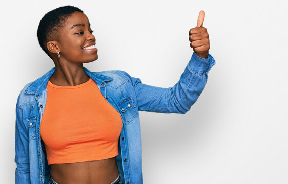 Young african american woman wearing casual clothes looking proud, smiling doing thumbs up gesture to the side