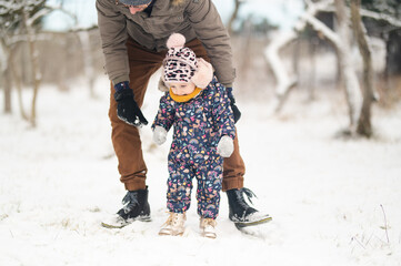 Father and baby girl playing in the snow during wintertime