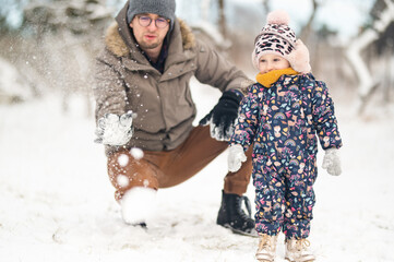 Father and baby girl playing in the snow during wintertime