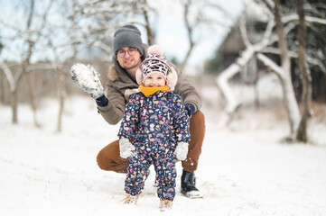 Father and baby girl playing in the snow during wintertime