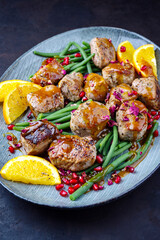 Modern style jusy seared pork pigllet tenderloin fillet meat medallions with orange relish sauce, pomegranate and green baby beans vegetable served as close-up on a Nordic design plate