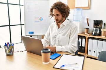 Young hispanic businessman with relaxed expression working at office.