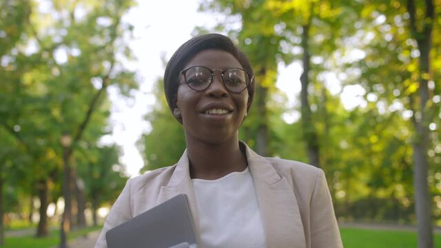 Successful confident African American business woman smiling, standing in park