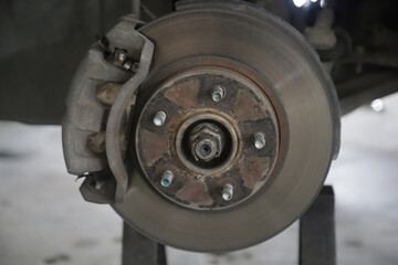 Disc brake of the vehicle for repair, in process of new tire replacement. Car brake repairing in garage. Close up.