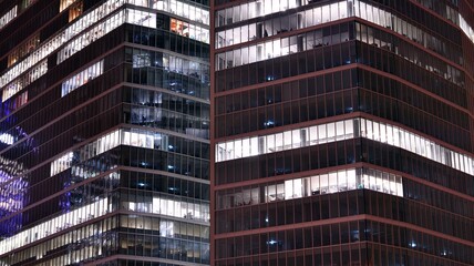 Fototapeta na wymiar Office building at night, building facade with glass and lights. View with illuminated modern skyscraper.