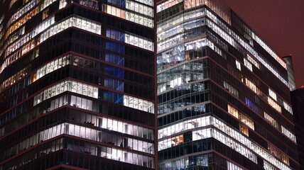 Fototapeta na wymiar Office building at night, building facade with glass and lights. View with illuminated modern skyscraper.