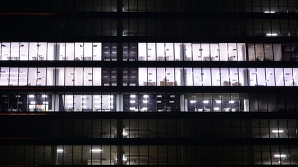 Fototapeta Office building at night, building facade with glass and lights. View with illuminated modern skyscraper. obraz