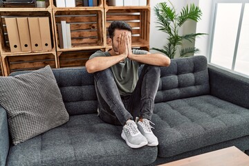 Obraz premium Young hispanic man psychology patient depressed sitting on sofa at clinic