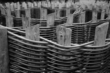 Selective focus on wooden fence posts of intertwined plastic pipes. Polypropylene plumbing pipes in landscape design. Abstract background. Black and white image.