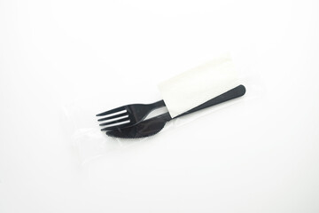 Clean plastic black forks and knives on white background. Disposable dishes, environmental pollution.