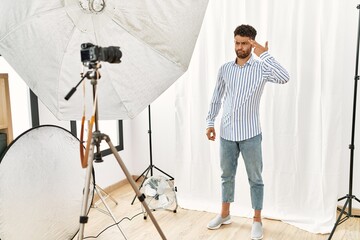 Arab young man posing as model at photography studio shooting and killing oneself pointing hand and fingers to head like gun, suicide gesture.
