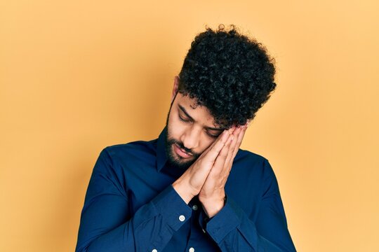 Young arab man with beard wearing casual shirt sleeping tired dreaming and posing with hands together while smiling with closed eyes.