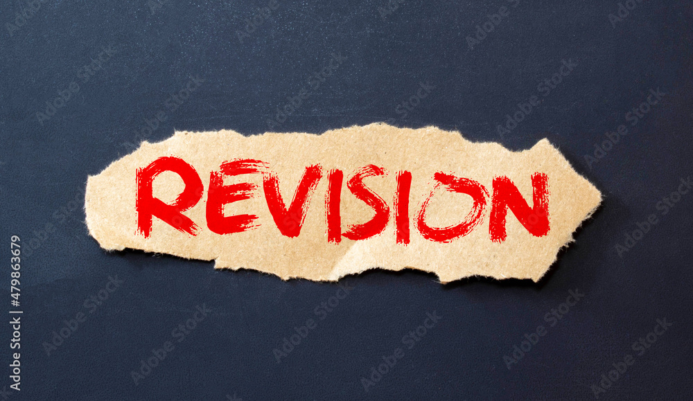 Poster beneath the torn strip of kraft paper attached with a red button is a white paper labeled revision