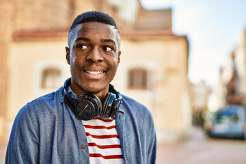 Young african american man smiling happy using headphones at the city.