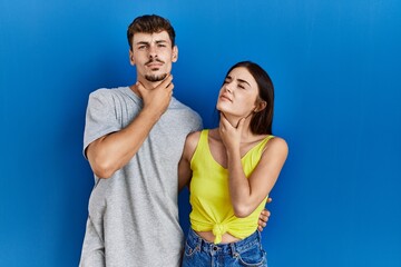 Obraz premium Young hispanic couple standing together over blue background touching painful neck, sore throat for flu, clod and infection