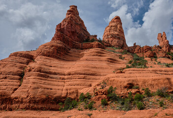 Fototapeta na wymiar Streaker Spire (left), Christianity Spire and the White Line, Sedona, Arizona. The White Line, halfway up the rock face, is a popular challenge for mountain bikers.