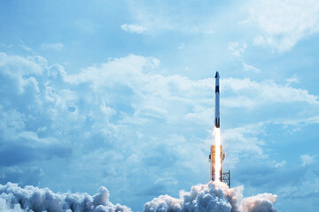 Take off space rocket on a background of blue sky and sun. Elements of this image were furnished by...