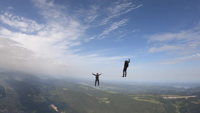 Sky divers free fall above green landscape