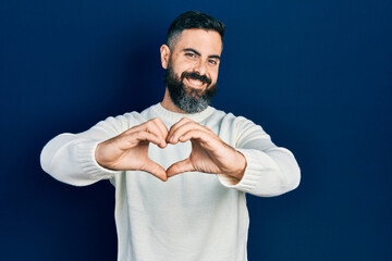 Fototapeta premium Young hispanic man wearing casual clothes smiling in love doing heart symbol shape with hands. romantic concept.