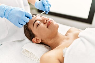 Fototapeta na wymiar Young latin woman relaxed having eyebrows treatment at beauty center