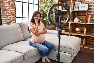 Fototapeta na wymiar Young pregnant woman recording vlog tutorial with smartphone at home thinking looking tired and bored with depression problems with crossed arms.