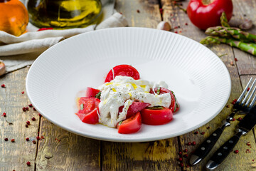 Salad with buratta cheese and red tomatoes on wooden table