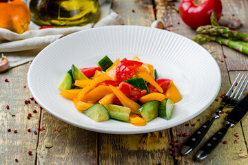 Vegetable salad with tomatoes and cucumbers and peppers on wooden table
