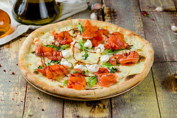 Pizza with salmon, shrimps and Philadelphia cheese on wooden table