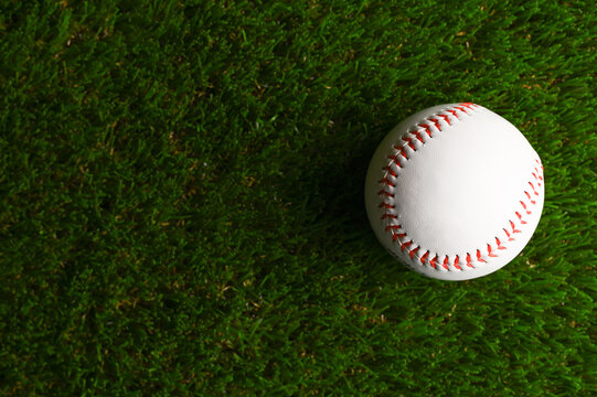 Close-up. Baseball ball on a green sports arena. There are no people in the photo. There is an empty space for insertion. Sports games, baseball, outdoor activities, healthy lifestyle.