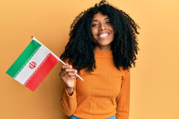 African american woman with afro hair holding kurdistan flag looking positive and happy standing...