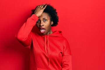 Young african american woman wearing casual sweatshirt surprised with hand on head for mistake,...