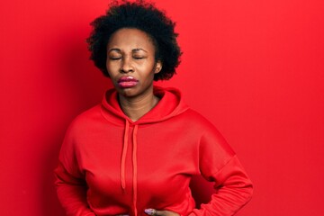 Obraz na płótnie Canvas Young african american woman wearing casual sweatshirt with hand on stomach because indigestion, painful illness feeling unwell. ache concept.