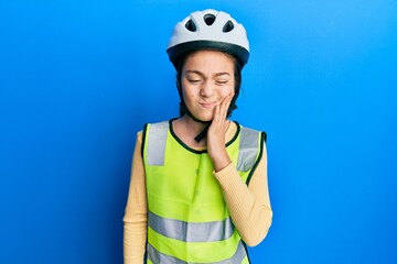 Beautiful brunette little girl wearing bike helmet and reflective vest touching mouth with hand with painful expression because of toothache or dental illness on teeth. dentist
