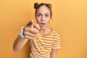 Beautiful brunette little girl wearing casual striped t shirt pointing displeased and frustrated to...
